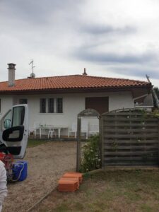 Maison avec terrasse et voiture ouverte.