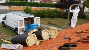 Travailleurs isolent un toit avec des rouleaux.