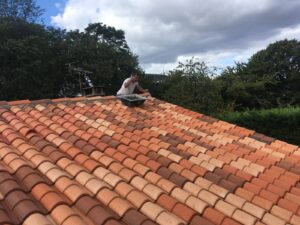 Homme travaillant sur un toit en tuiles.